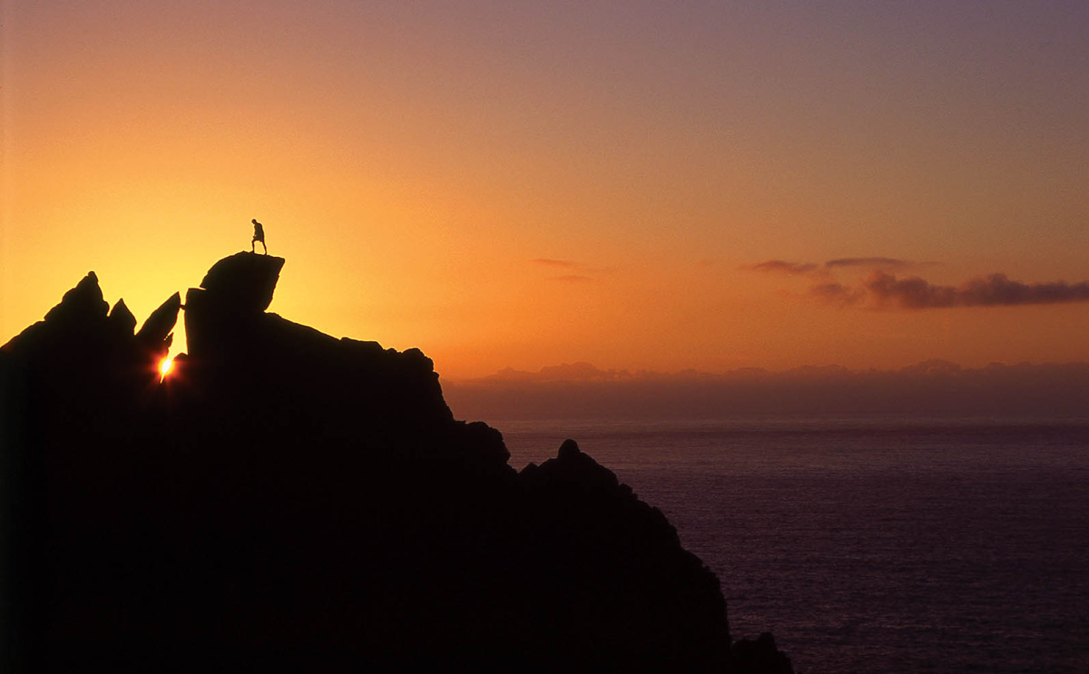As the sun sets on another beautiful Cornish day a climber stands atop the VD, Bosigran Ridge (Commando Ridge) during a solo ascent of this classic route. Photo: © David Simmonite